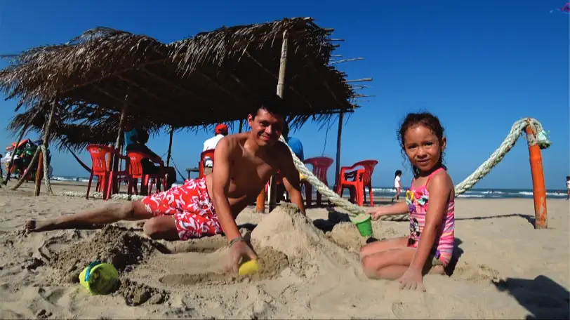 Papa e hija disfrutando de sol ne la playa